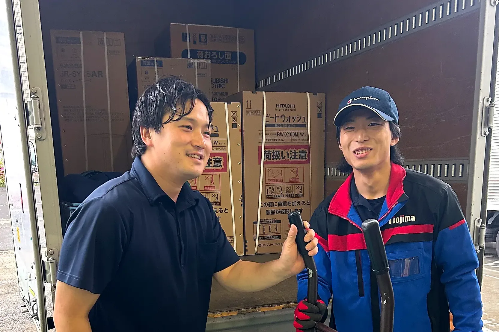 トラックの荷台の前で笑い合う2人